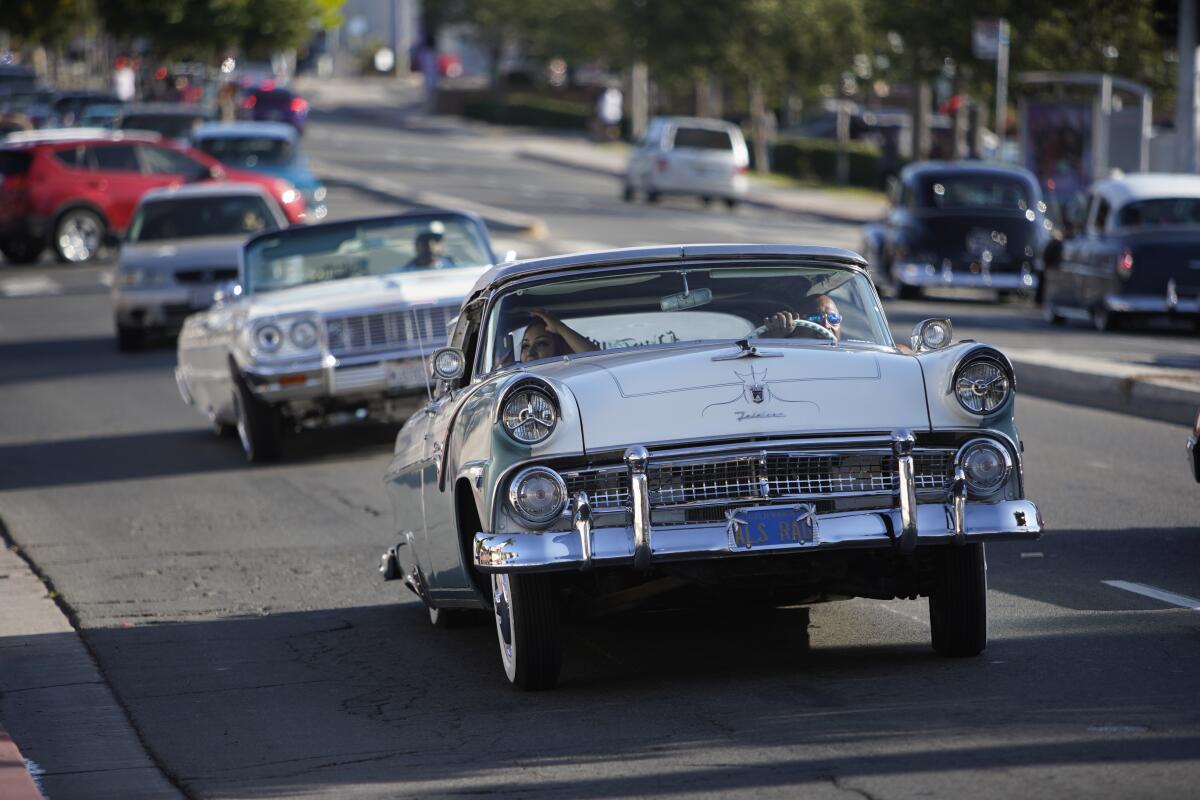 Lowriders drive down a city street