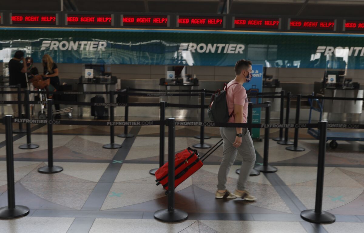FILE - A lone traveler heads to the ticketing counter of Frontier Airlines in the main terminal of Denver International Airport on July 22, 2020, in Denver. Hotel and home-sharing reservation site Booking.com plans to lay off 25% of its workforce, or more than 4,000 people, due to the impact of the new coronavirus on travel. Connecticut-based parent company Booking Holdings said Tuesday, Aug. 4, that the layoffs will begin next month. (AP Photo/David Zalubowski, File)