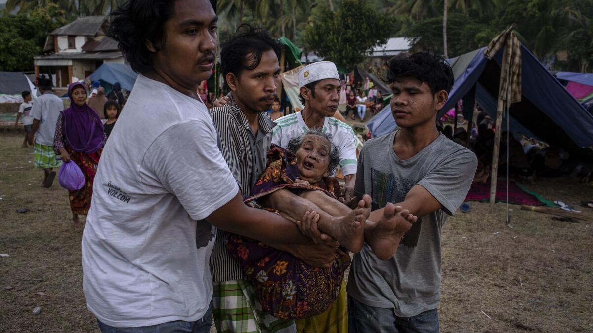 Indonesians at a temporary shelter carry an elderly woman Aug. 7 on Lombok Island, Indonesia. Nearly 100 people have been confirmed dead after a 6.9-magnitude earthquake hit the Indonesian island,