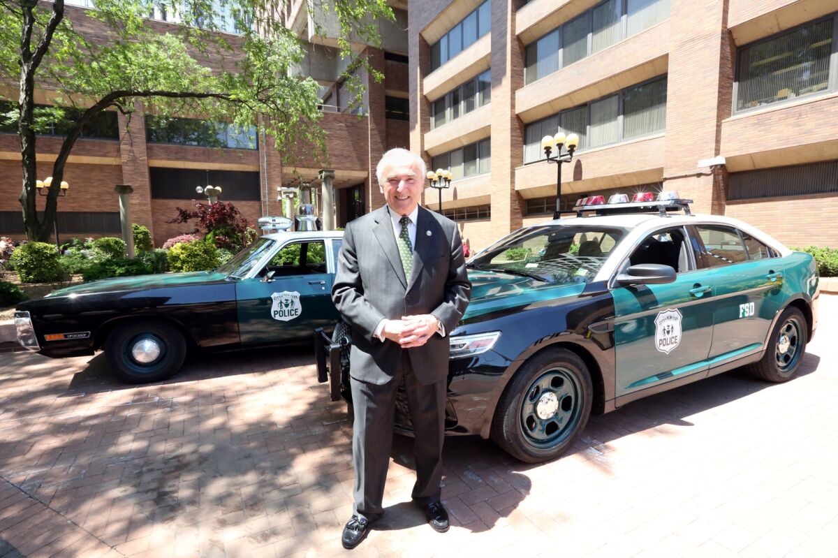 Bill Bratton in front of a two cars.
