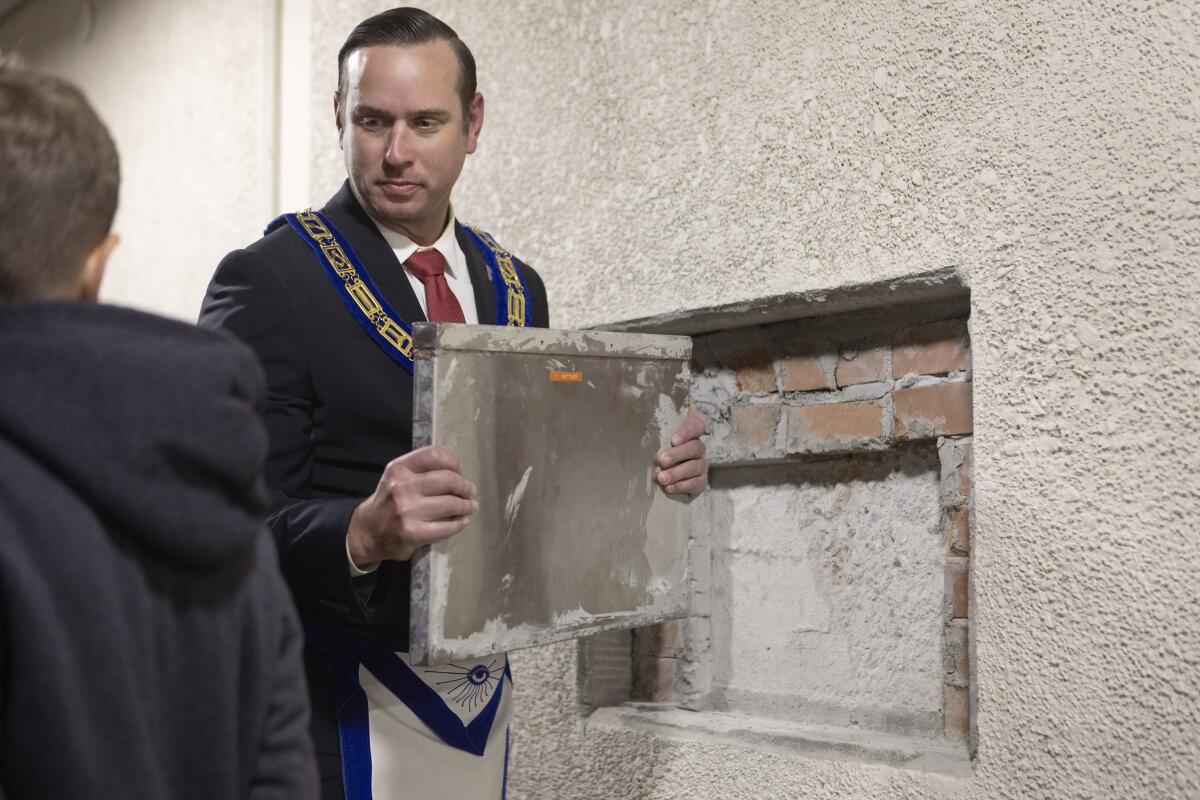 Freemason Joshua Lowe removes a time capsule from a wall of the former Kettler Elementary School in Huntington Beach.