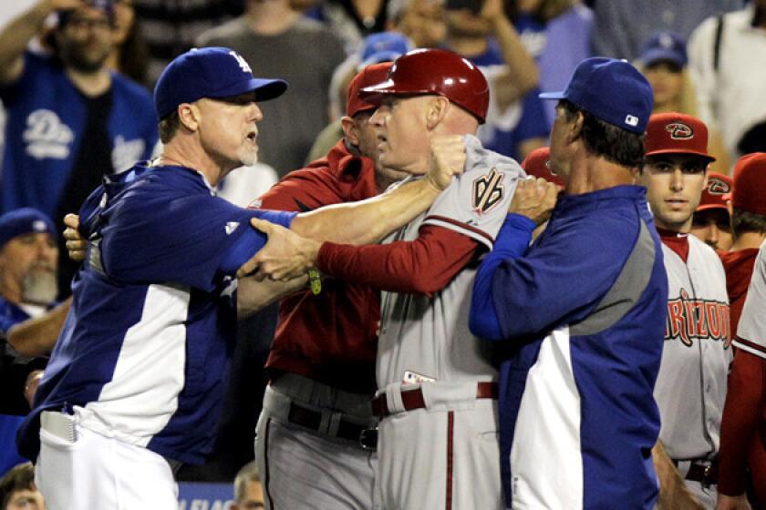 Dodgers hitting coach Mark McGwire, left, and Dodgers Manager Don Mattingly grab onto Arizona Diamondbacks third base coach Matt Williams after Dodgers starting pitcher Zack Greinke was hit by a pitch and both benches cleared.