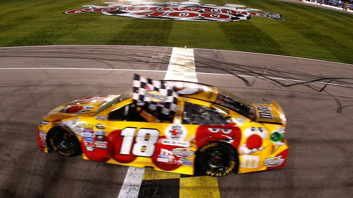 NASCAR driver Kyle Busch celebrates with the checkered flag after winning the Sprint Cup Series race at Kansas Speedway on Saturday night.