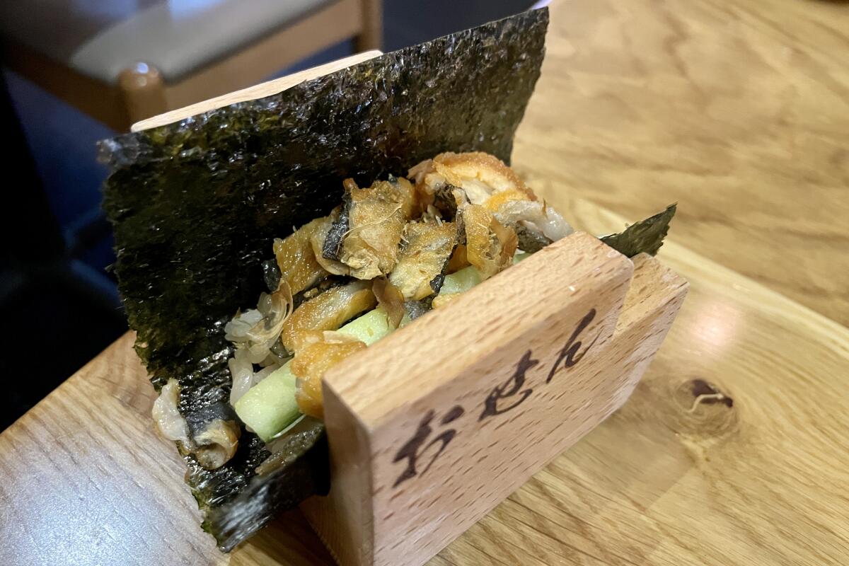 The salmon skin hand roll is served in a wooden stand to hold it together