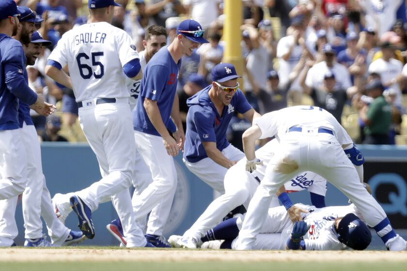 LOS ANGELES, CA -- AUGUST 07, 2019: Dodgers Russell Martin (on ground) gets mobbed by teammates after his walkout single drove in two runs to beat the Cardinals 2-1 Wednesay. (Myung J. Chun / Los Angeles Times)