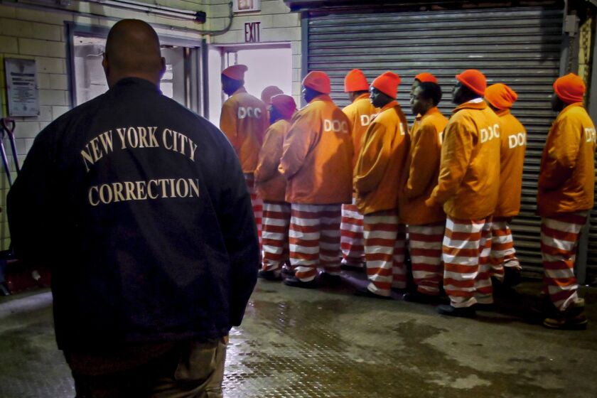 FILE - In this March 16, 2011 file photo, a corrections official watches inmates file out of a prison bakery after working the morning shift at the Rikers Island jail in New York. New York City’s notorious Rikers Island jail complex, troubled by years of neglect, has spiraled into turmoil during the coronavirus pandemic. (AP Photo/Bebeto Matthews, File)