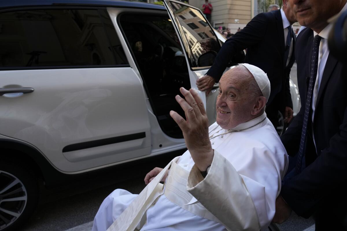 Pope Francis waves as he prepares to enter a vehicle.