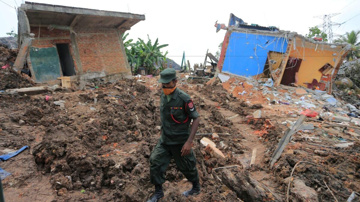 A Sri Lankan army soldier walks past damaged houses on April 17 after a garbage collapse in Meetotamulla.