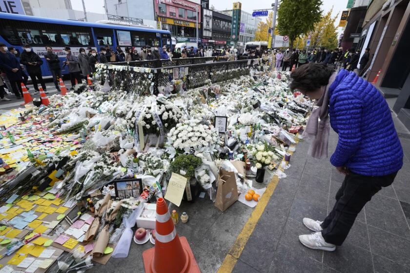 A woman bows to pay tribute to victims of a deadly accident that happened during Saturday night's Halloween festivities, at a makeshift flower-laying area set up near the scene of the accident in Seoul, South Korea, Thursday, Nov. 3, 2022. (AP Photo/Ahn Young-joon)