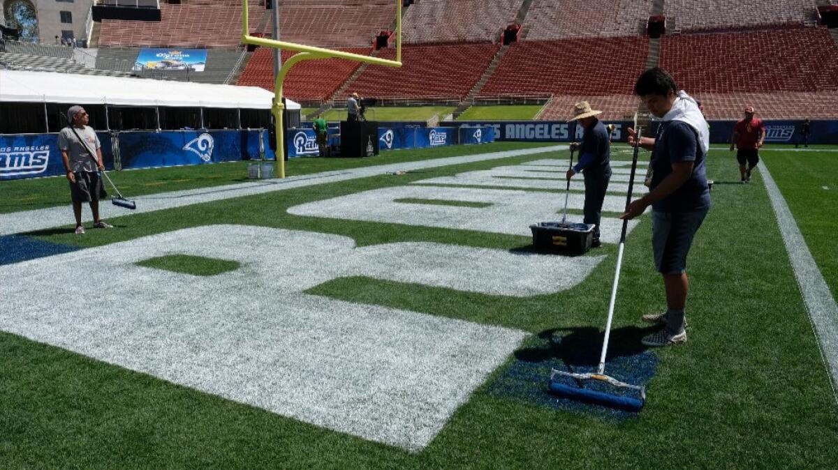 Crew members paint the end zone ahead of the Rams' Saturday preseason matchup with the Dallas Cowboys at the Coliseum.