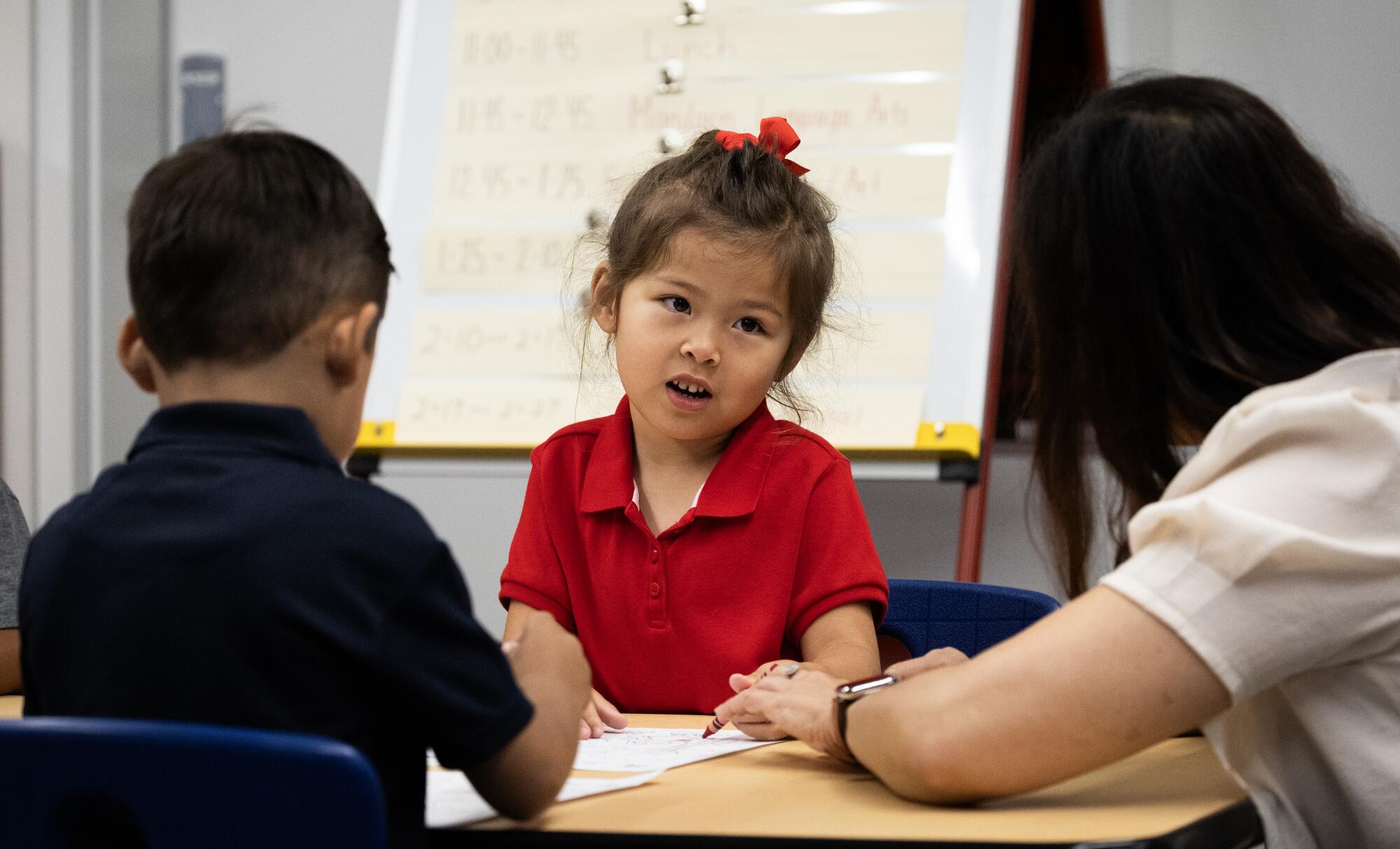 A teacher leans toward a speaking child.