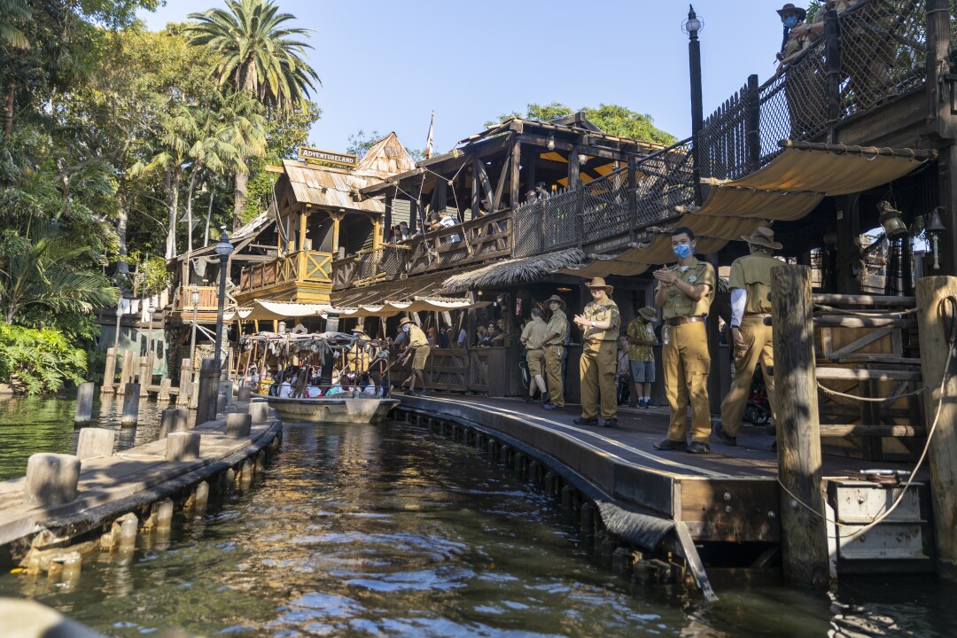 Passengers disembark the Jungle Cruise ride while staff in khakis applaud