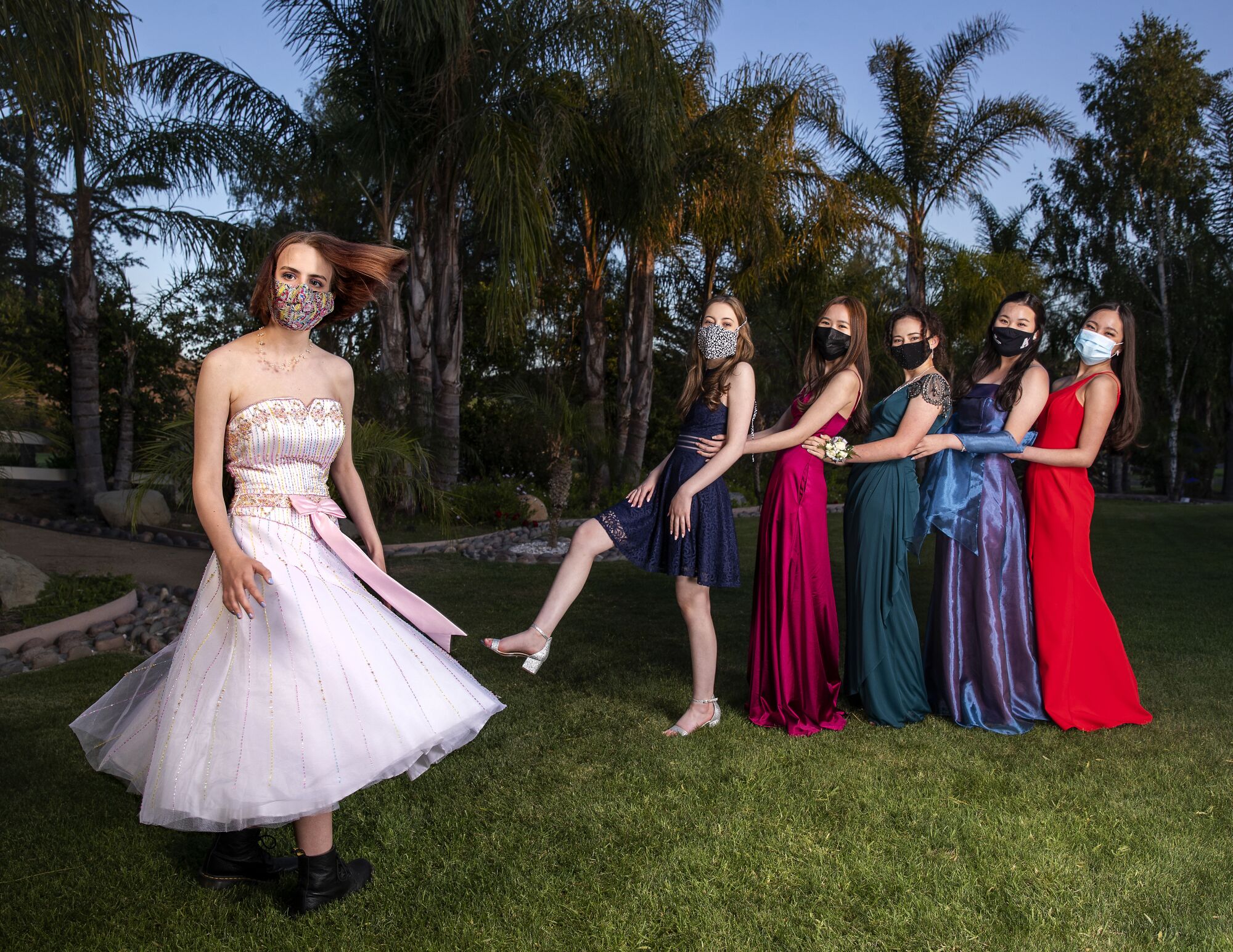 Students line up in masks and formal gowns.