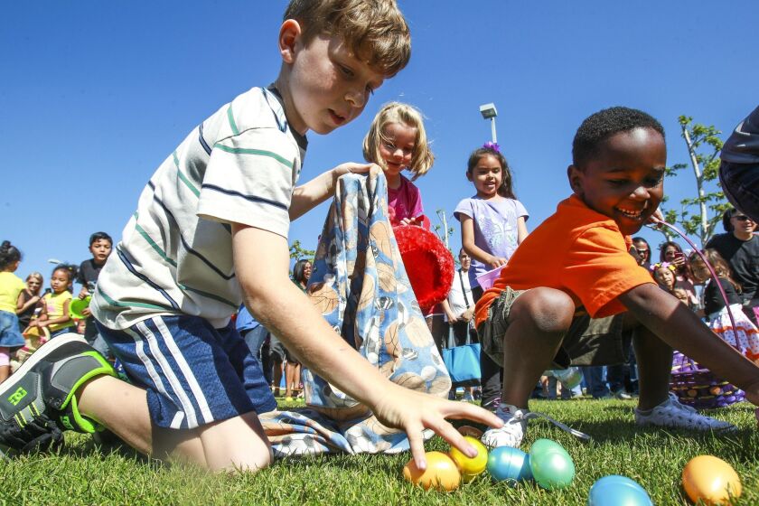A pair of boys reach for Easter eggs as they and other children, ages 4-7, hunt fir eggs.