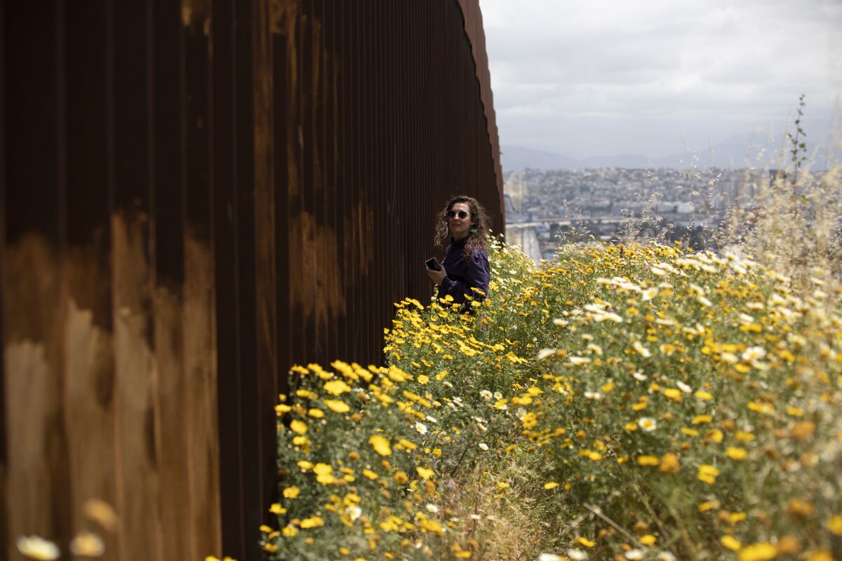 Journalist's Notebook: What I learned from listening to asylum seekers around the world 2 Reporter Kate Morrissey of the San Diego Union-Tribune stands next to the border wall on the Tijuana side
