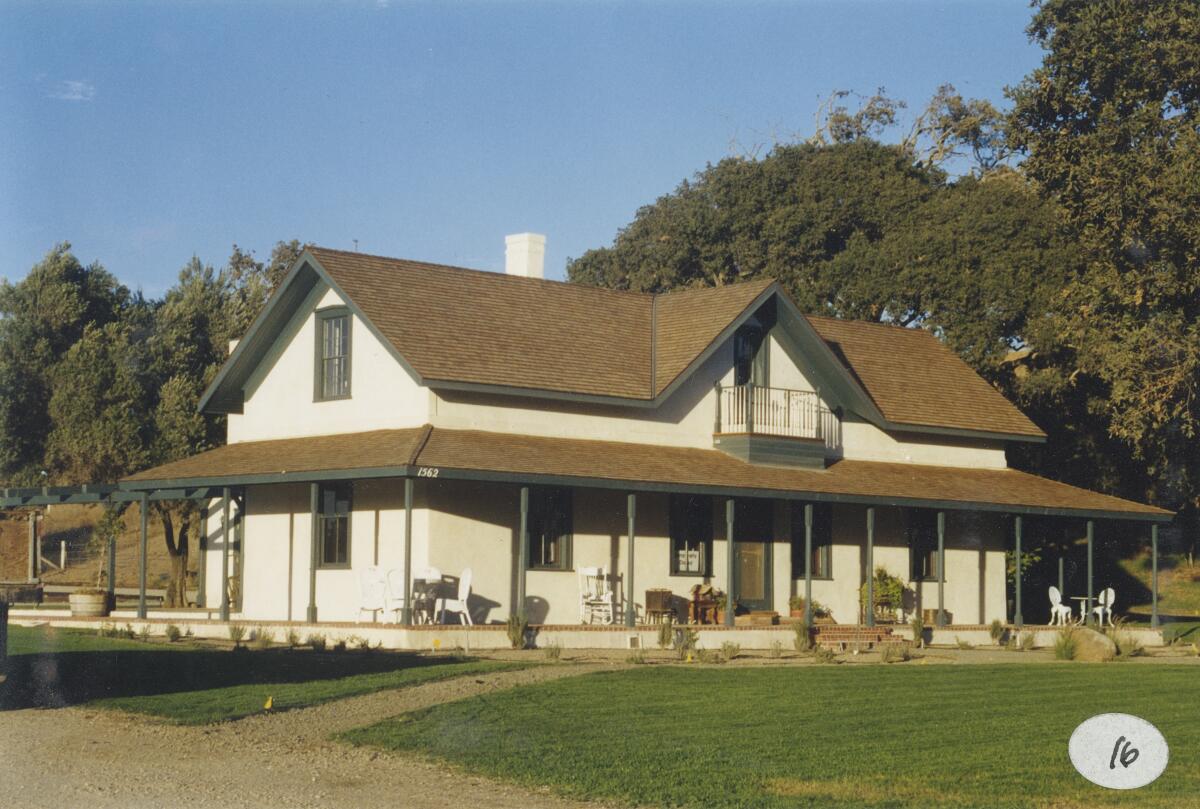 A two-story house with a wraparound porch and wide, green lawn