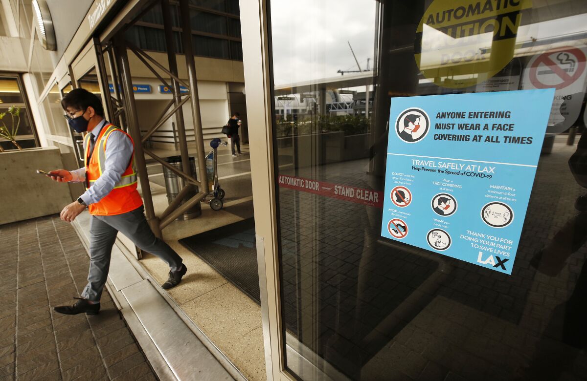 A sign at Los Angeles International Airport informs travelers that they must wear a mask or other face covering.