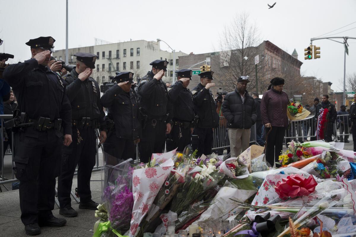 Fellow officers salute before a makeshift memorial near the site where New York City police Officers Rafael Ramos and Wenjian Liu were ambushed and killed in Brooklyn in December 2014.