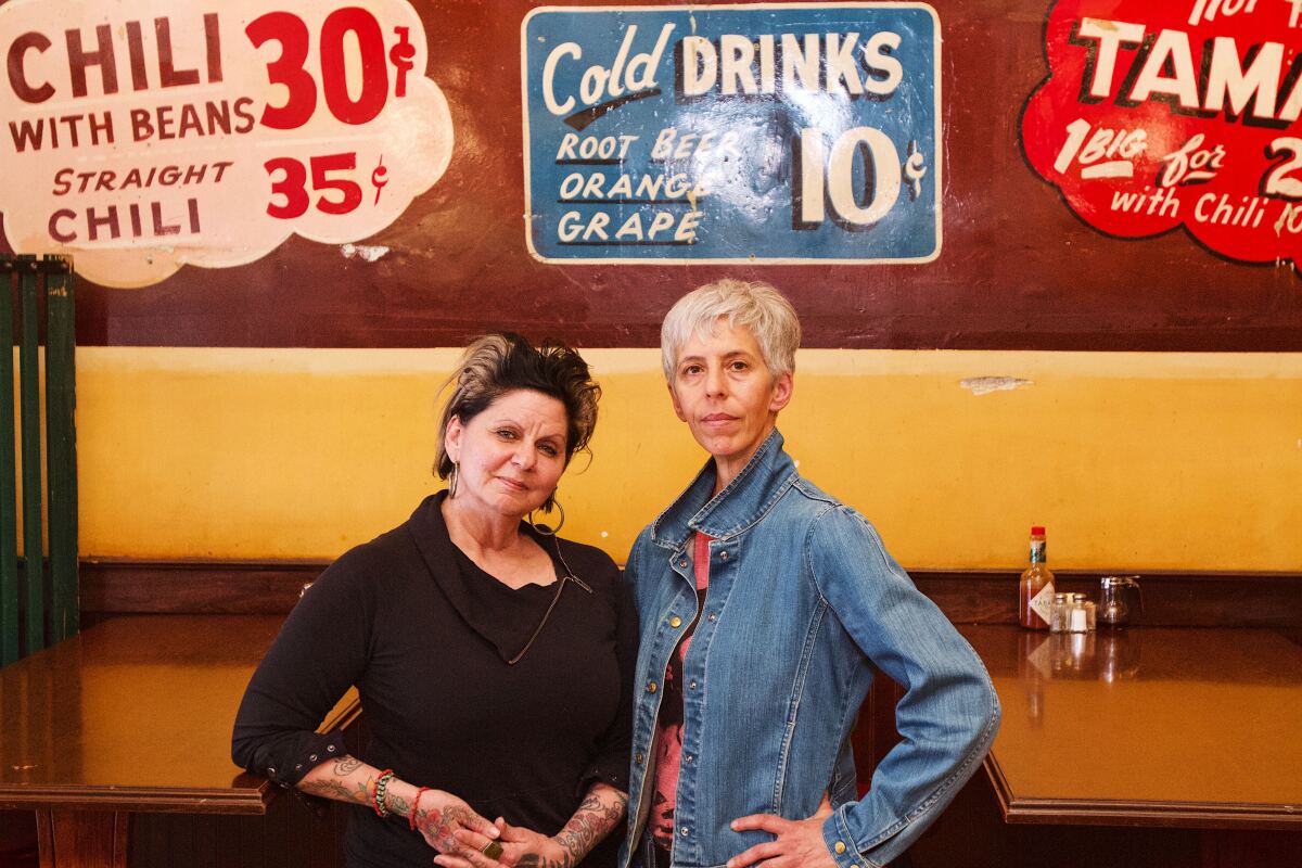 The two Nickel Diner owners stand in front of original 1940s sign painted on the restaurant's wall