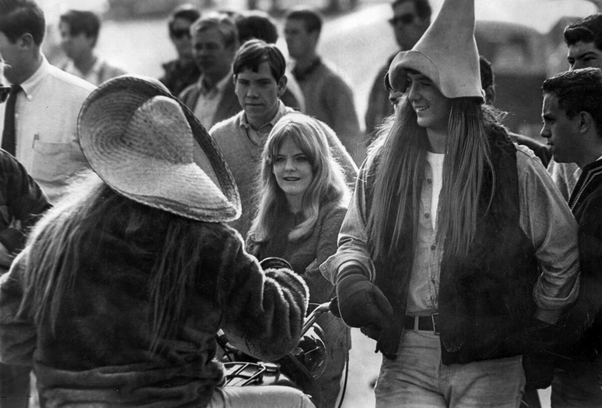 March 10, 1966: Former Palisades High School students Tom Lazich, 19, in the pointed hat and wig, and Stubby Stammer, also 19, on a motorcycle, show up at the school to support a protest by long-haired students told by officials to get haircuts.