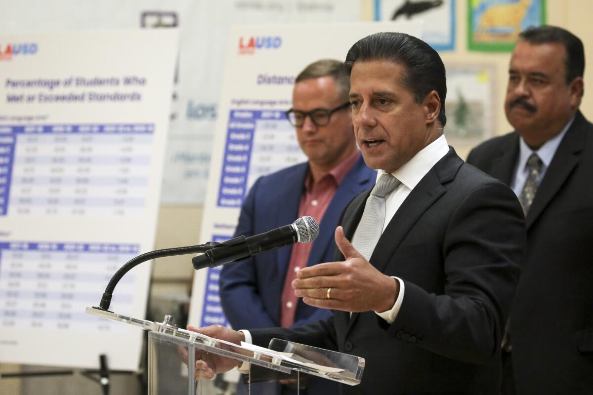 Alberto Carvalho stands in front of charts revealing test scores. 