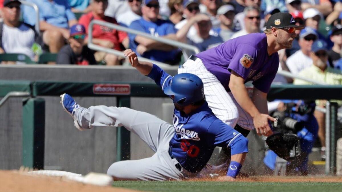 Dodgers outfielder Brett Eibner slides safely into third as Colorado Rockies first baseman Mark Reynolds takes the throw on March 6.