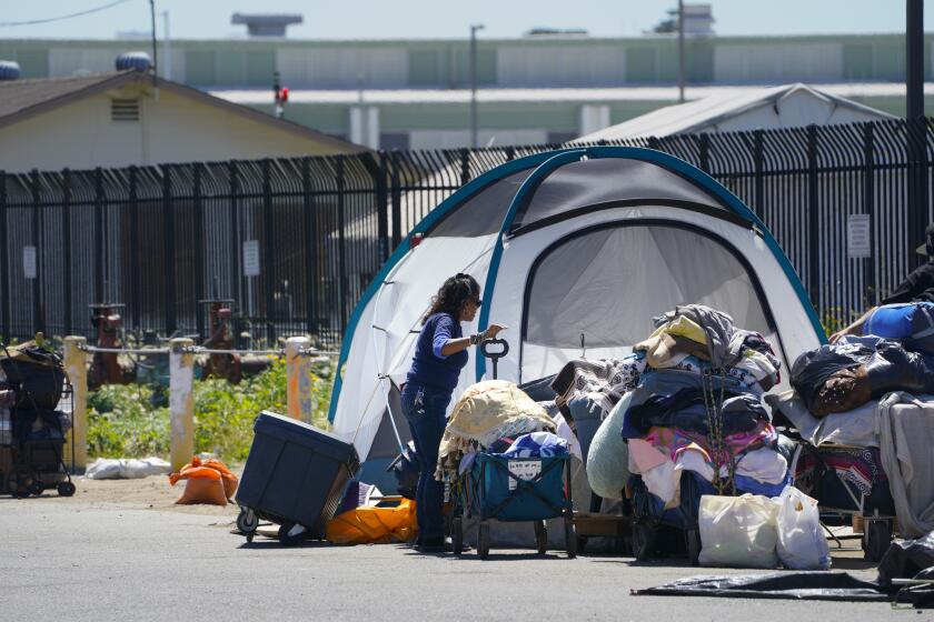 San Diego, CA, April 16: On Tuesday, April 16, 2024, at an encampment in Point Loma in San Diego, CA, Della Infante (l), 59, relocates her tent and personal items to the other side of the street. Because of a recent abatement notification at the encampment, everyone is required to move to one side of the street, so that a cleanup crew can do their work. (Nelvin C. Cepeda / The San Diego Union-Tribune)