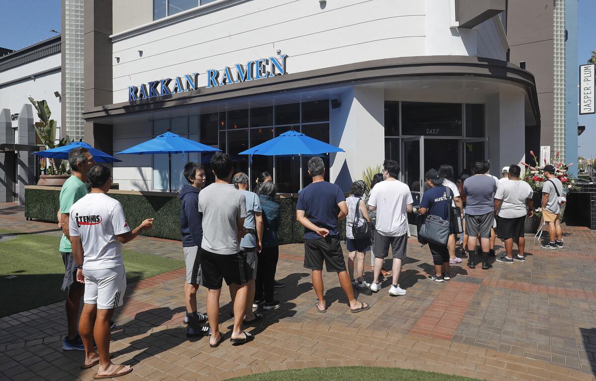 Guests wait in line for the opening of Rakkan Ramen, a Japanese ramen brand, at the District at Tustin Legacy on Monday.