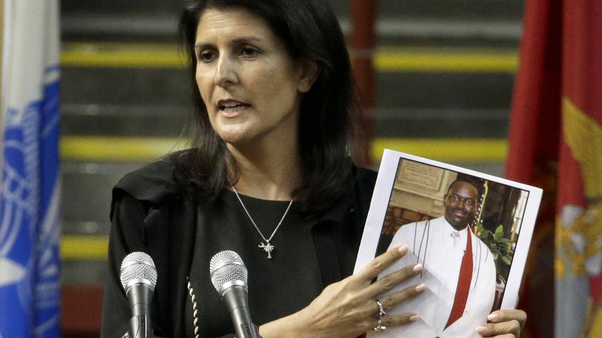 South Carolina Gov. Nikki R. Haley holds a photo of Clementa C. Pinckney as she speaks during a memorial service on the anniversary of last year's deadly shooting at a Charleston church.