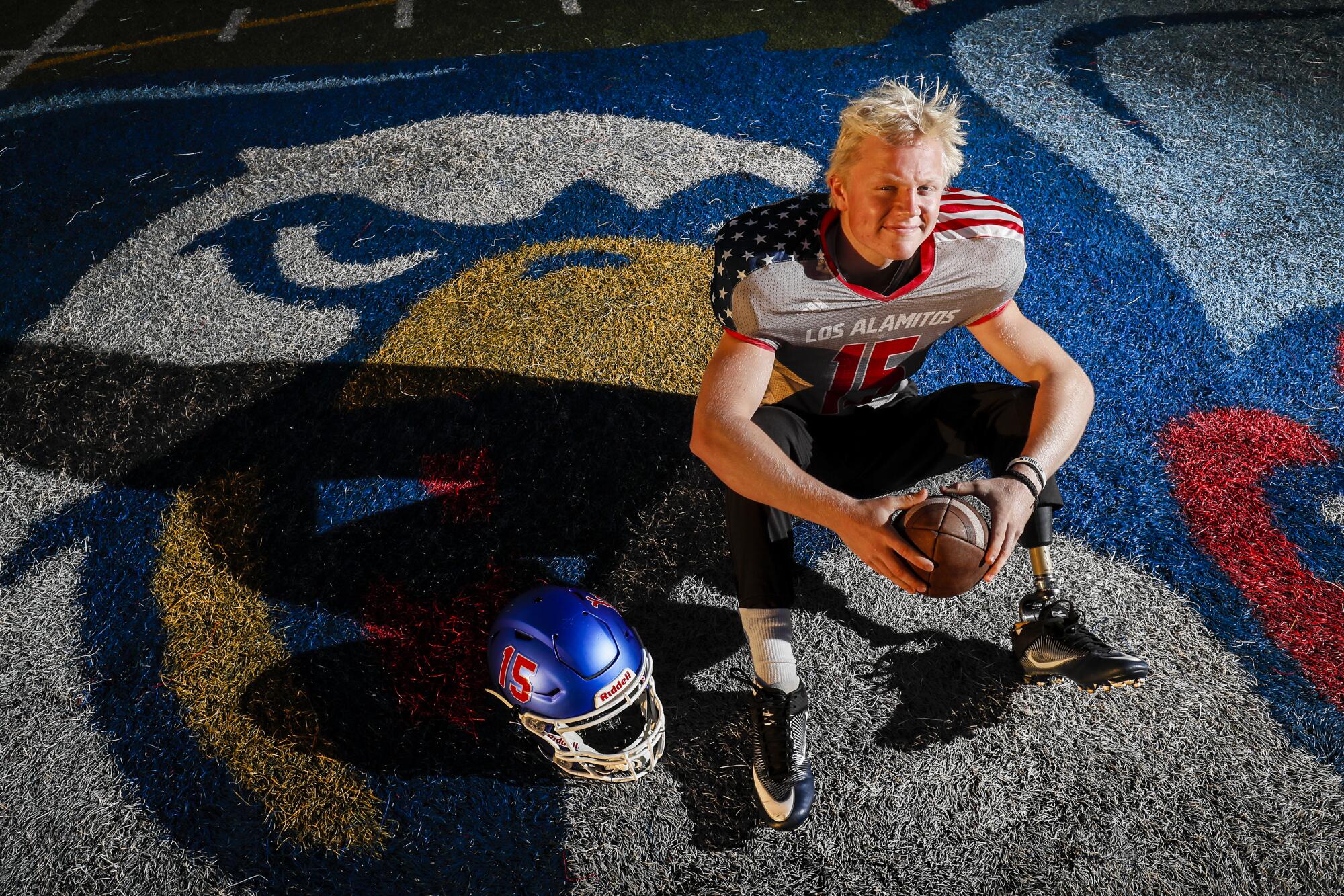 Los Alamitos long snapper Carson Fox sits on the field looking at the camera.