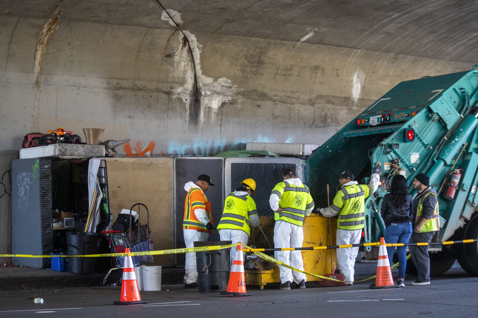 Workers clean up a homeless encampment.
