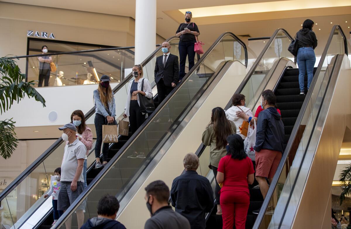 Shoppers on escalators at South Coast Plaza wear masks.