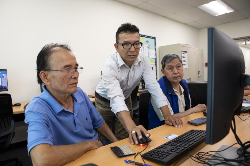 San Diego, California - July 20: Zulfiqar Noori, center, helps Du Trang, left, and Thanh Vuong with registering for classes at San Diego College of Continuing Education on Thursday, July 20, 2023 in San Diego, California. Noori is from Afghanistan and resettled in San Diego. He is currently taking classes for cyber security. (Ana Ramirez / The San Diego Union-Tribune)