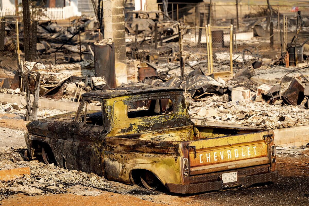 FILE - A scorched pickup truck sits in front of a Wakefield Avenue home destroyed by the Mill Fire on Saturday, Sept. 3, 2022, in Weed, Calif. A wood products company said Wednesday, Sept. 7, 2022 that it is investigating whether a fire that killed two people as it swept through a Northern California town was caused by the possible failure of a water-spraying machine used to cool ash at its veneer mill. (AP Photo/Noah Berger, File)