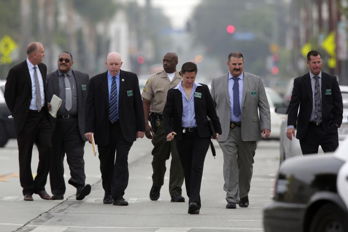 Los Angeles County Sheriff's Department investigators walk along Seville Avenue in Walnut Park after a deputy-involved shooting that left a 31-year-old man dead.