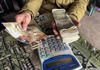 Inside Actionha cafe shop in Deir al-Balah, people handle cash with a calculator