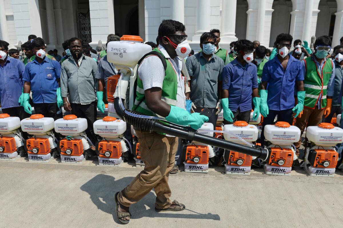 Health workers prepare to spray disinfectant outside municipal offices in Chennai, India
