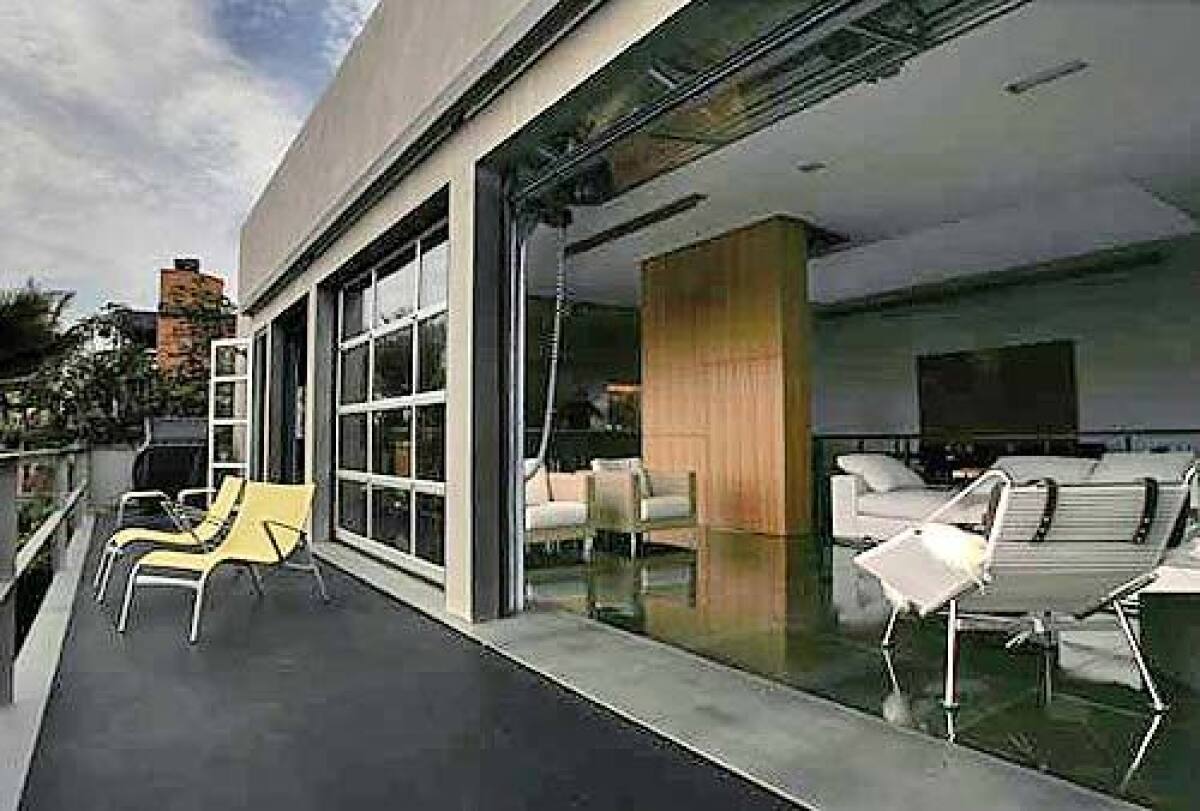 Aluminum-and-glass doors inspired by British firehouses and made in the United Kingdom fold upward electronically to bring the outdoors into the living room.