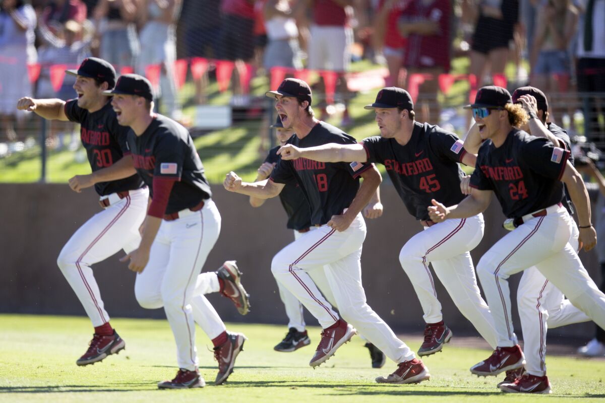 Stanford players erupt from the dugout after the final out secured their victory over Connecticut in an NCAA college baseball tournament super regional game, Monday, June 13, 2022, in Stanford, Calif. (AP Photo/D. Ross Cameron)