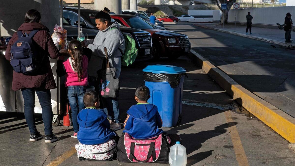 Asylum seekers eat outside the El Chaparral port of entry as they wait for a turn to present themselves to U.S. border authorities to request asylum in Tijuana on April 9.