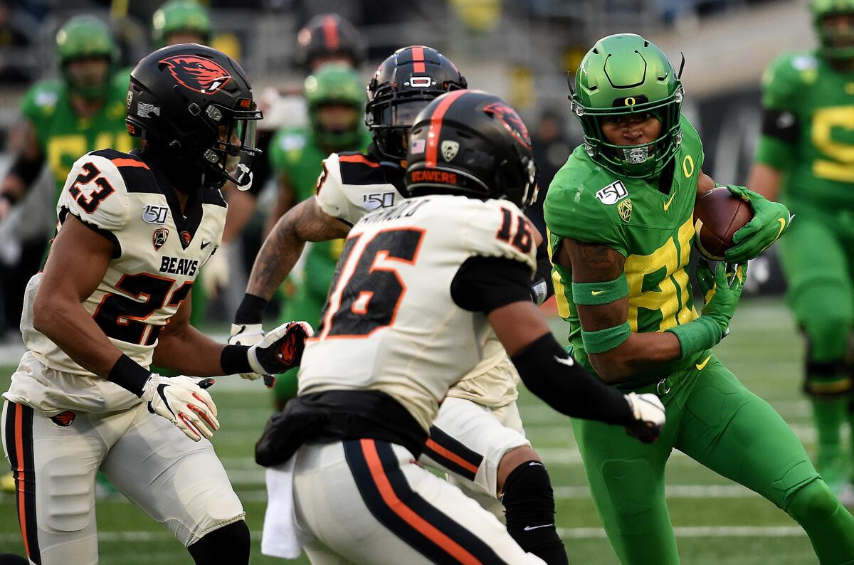 Oregon wide receiver Bryan Addison (80) runs with a pass reception as Oregon State defensive back Isaiah Dunn (23) and defensive back Akili Arnold (16) close in during the second half on Saturday.