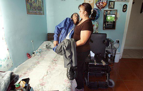 Salvador Chavez's sister, Juana Chavez, helps him into bed from his wheel chair for a 30-minute rest before he has dinner at their home in East Los Angeles.