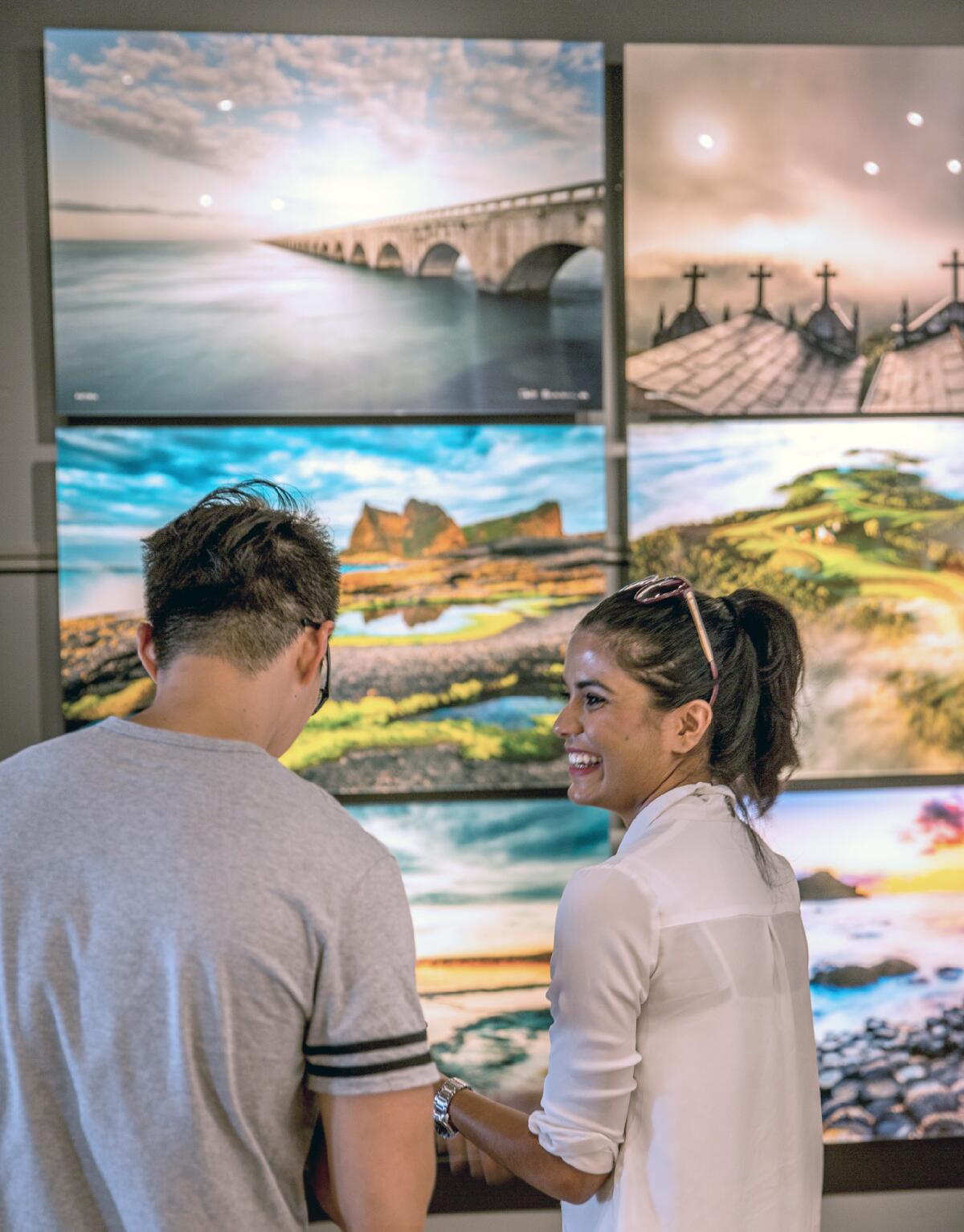 Rozy Akther, right, of Irvine talks with friend Wayne Wei about the photos in the new National Geographic fine art gallery, at 218 Forest Ave. in Laguna Beach.