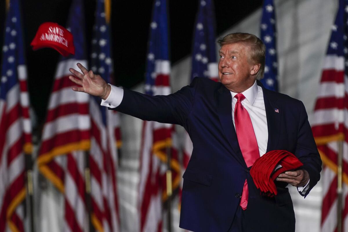 Former President Donald Trump tosses caps to the audience as he arrives at a rally Friday, Aug. 5, 2022, in Waukesha, Wis. (AP Photo/Morry Gash)