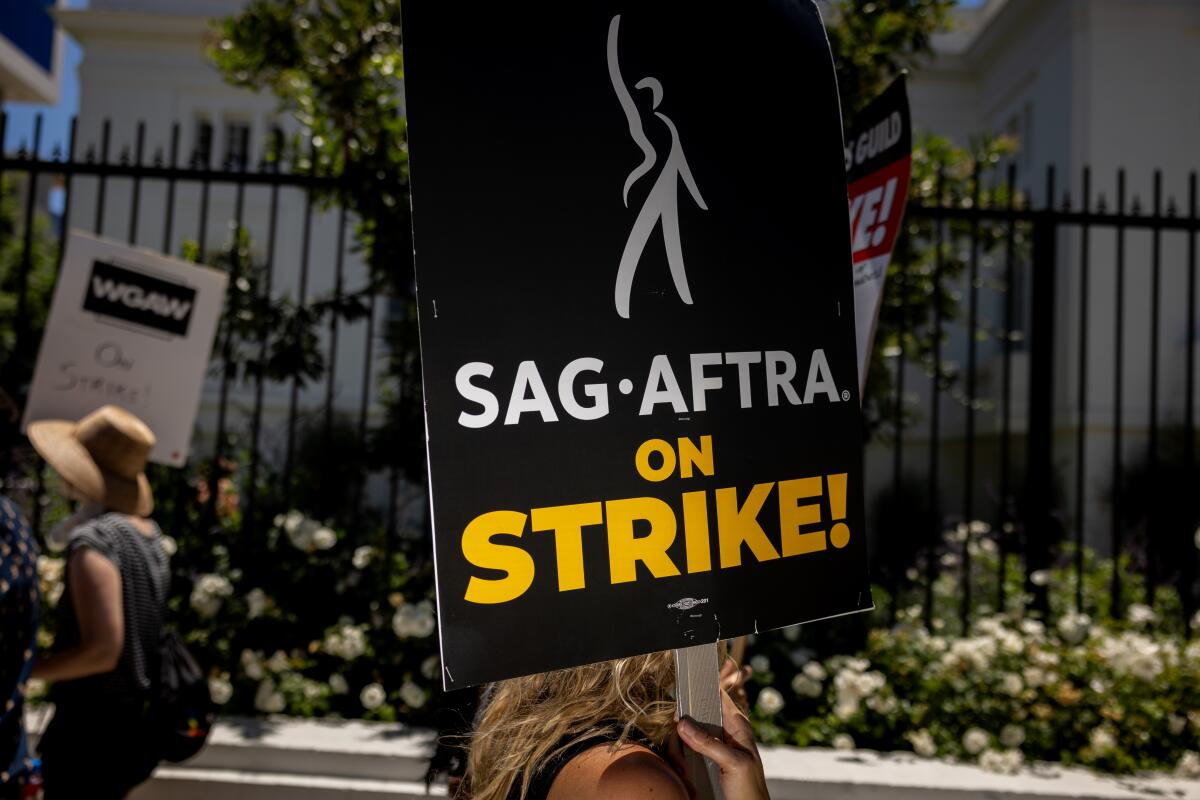 A sign that reads "SAG-AFTRA on Strike!" in front of a black fence 