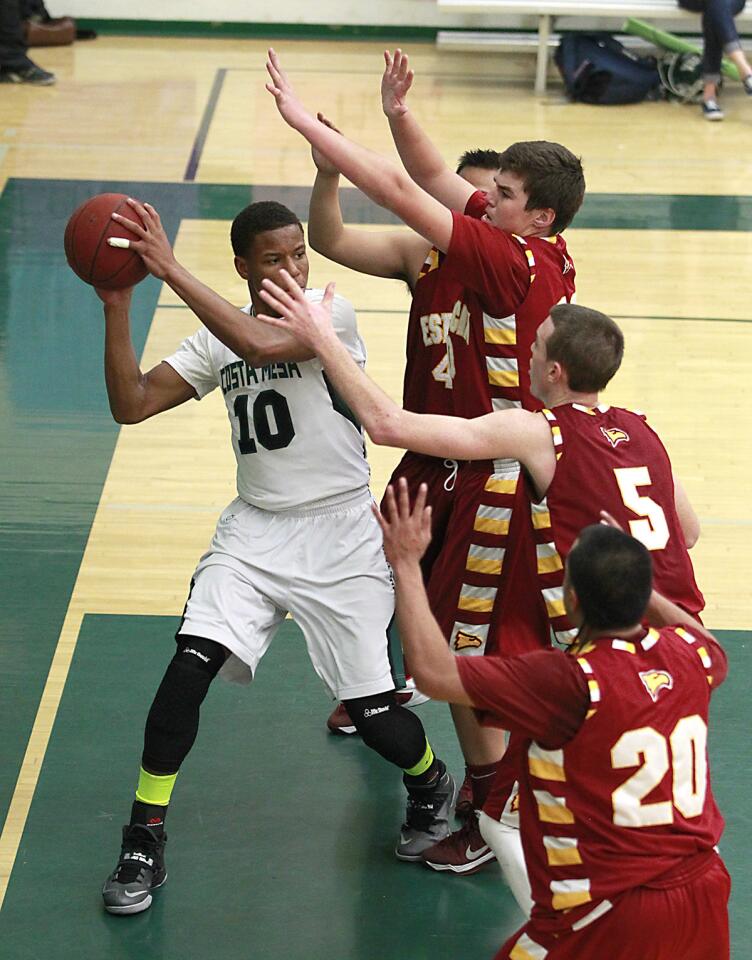 Costa Mesa's Quinton Bell is surrounded by Estancia defenders under the basket as he looks to pass during Orange Coast League game action on Wednesday at Costa Mesa.