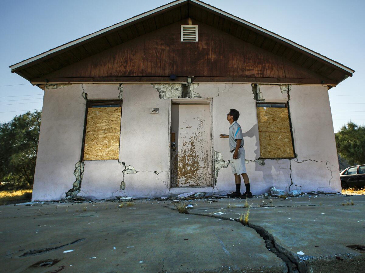 Jenner Kim, 50, of Trona examines his storage building, which was badly damaged by the Fourth of July quake.