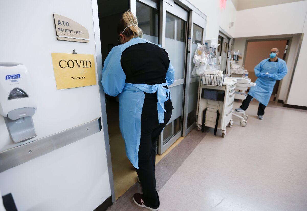 Hospital staff outside patient room with sign reading "COVID."