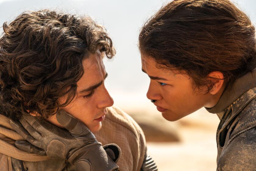 Zendaya's gloved hand caresses Timothée Chalamet's face in a scene from "Dune."