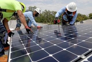 LOS ANGELES, CA - JUNE 18: Juan Alcantara, left, intern/trainee, Sal Miranda, supervisor, and Lee Kwok, solar installer supervisor, of GRID Alternatives, a nonprofit, install solar panels that will generate 5 kilowatts of energy at a low-income home in Watts on Friday, June 18, 2021 in Los Angeles, CA. A total of 15 327 watt panels were placed on the roof. (Gary Coronado / Los Angeles Times)